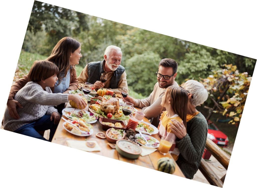Multi-generational happy family enjoying outdoor dinner meal celebration together at rustic dining table